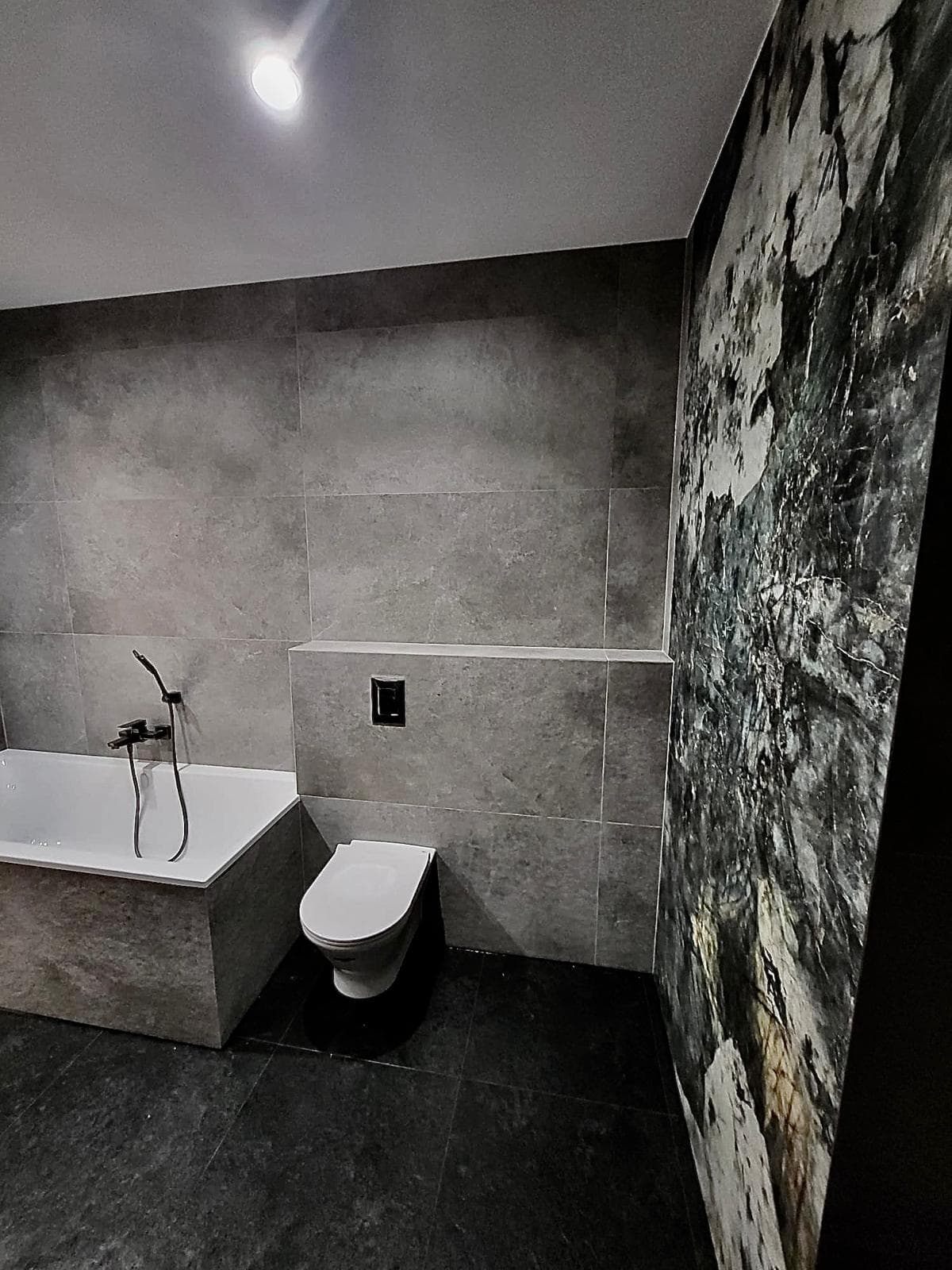 Nowoczesna łazienka z wanną, WC i marmurową ścianą akcentową — QR BUD